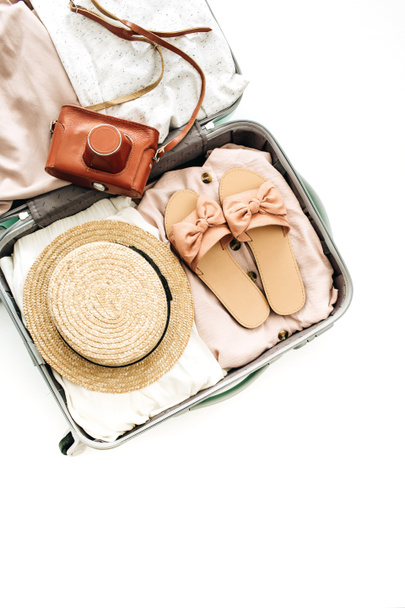 Hand luggage with feminine straw, slippers and retro camera on white background. Flat lay, top view. Summer fashion clothes and travel concept. - Photo, Image