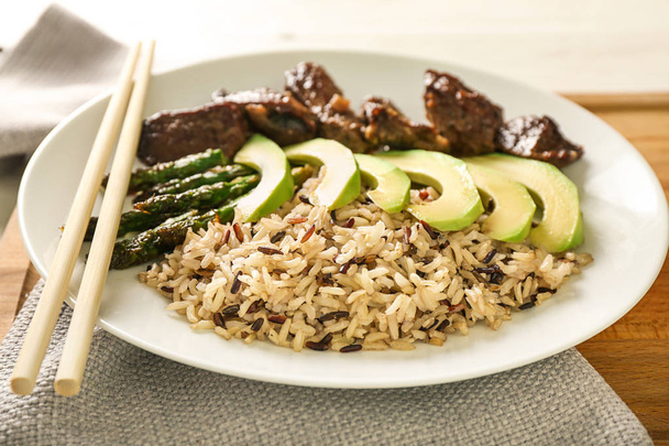 Тарілка з вареним рисом, овочами та м'ясом на дошці, крупним планом
 - Фото, зображення