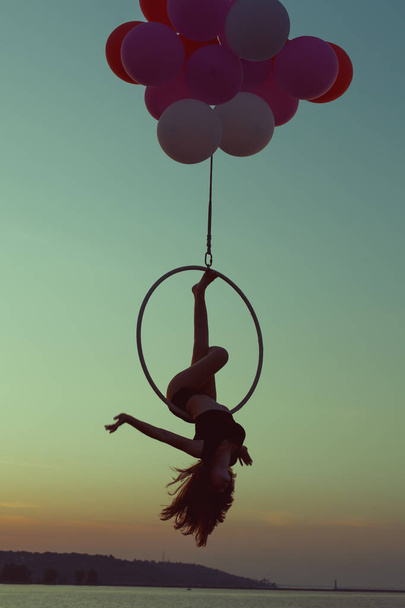 Fille gymnaste faire des tours sur l'anneau acrobatique au coucher du soleil
. - Photo, image