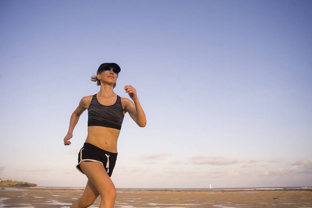 isolated background portrait of young happy and attractive fit woman running on the beach in outdoors jogging workout in fitness training and healthy sporty lifestyle concept - Fotografie, Obrázek