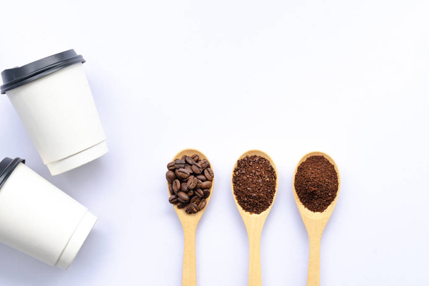 colheres de madeira cheias de grãos de café e café moído esmagado, xícara de papel e palavra de café no fundo branco
 - Foto, Imagem