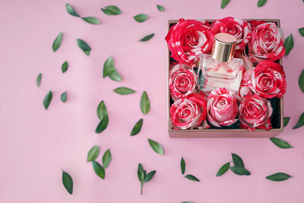 Laatikko pullo hajuvettä ja ruusuja värillinen tausta
 - Valokuva, kuva