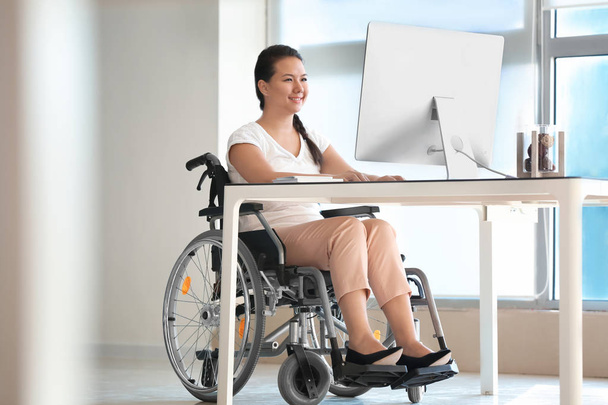 Ασιατικές γυναίκα στην αναπηρική καρέκλα εργασίας με τον υπολογιστή στο γραφείο - Φωτογραφία, εικόνα