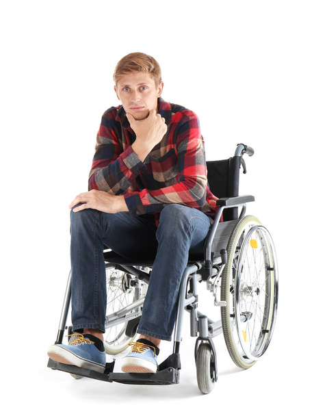 Thoughtful young man sitting in wheelchair on white background - Photo, Image
