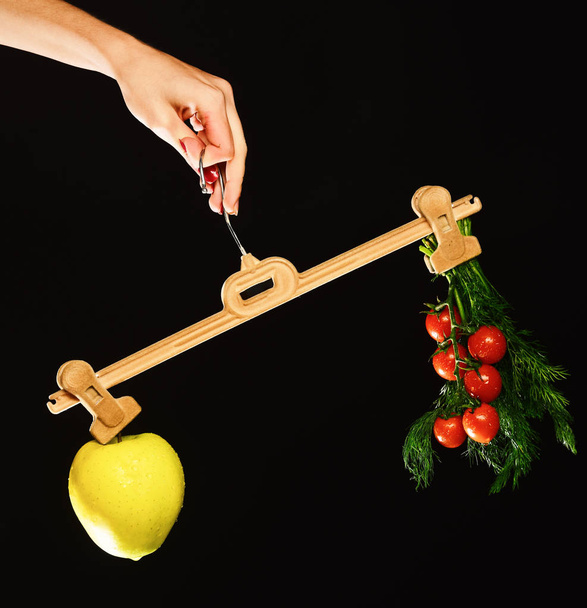 Female hand holds hanger with fruit and vegetables on tips - 写真・画像