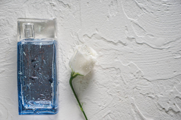 Fles met parfum en witte bloem op licht getextureerde achtergrond - Foto, afbeelding