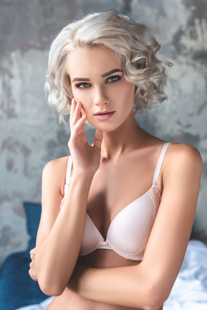 close-up portrait of seductive young woman in underwear standing in loft bedroom and looking at camera - Fotografie, Obrázek