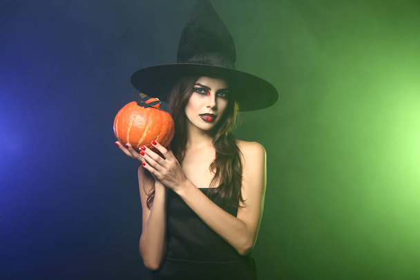 Beautiful woman dressed as witch for Halloween on color background - Foto, Bild