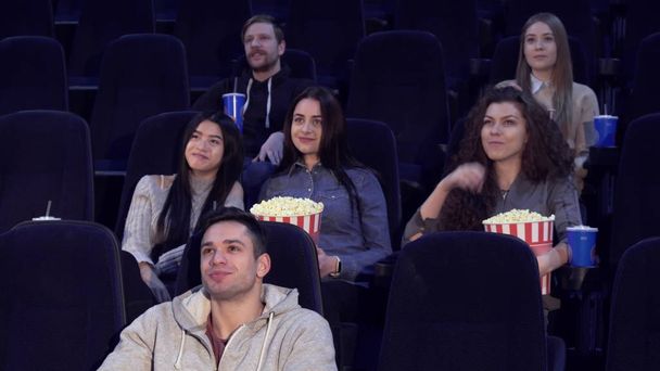 Молодые люди смотрят кино в кинотеатре
 - Фото, изображение