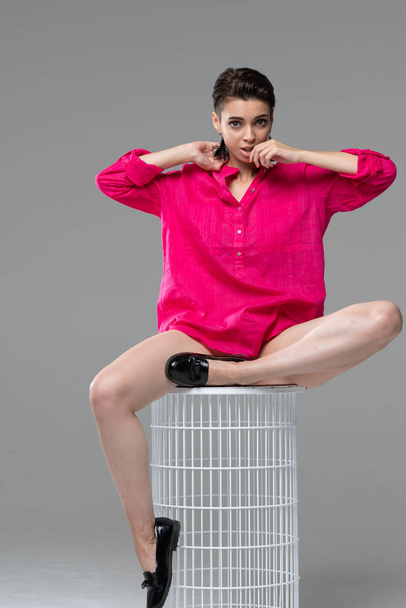 young beautiful girl posing in the studio, sitting on a chair in a red blouse - Photo, Image