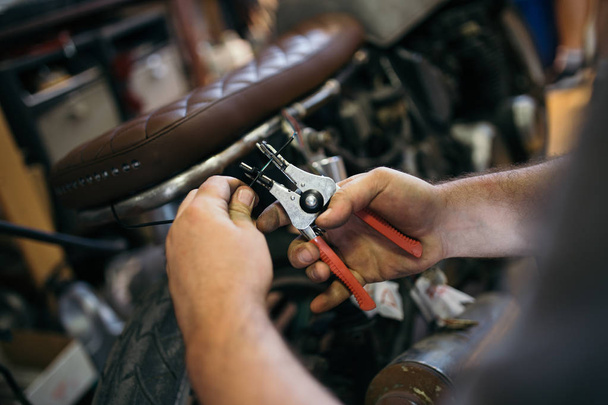 Close up shot of experienced man working in custom made motorcycle workshop.  - Fotó, kép