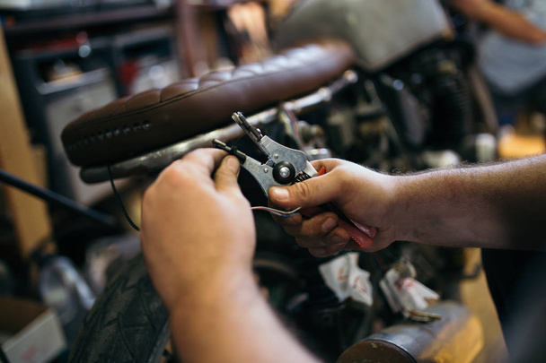 Close up shot of experienced man working in custom made motorcycle workshop.  - Photo, image