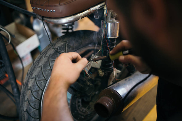 Close up shot of experienced man working in custom made motorcycle workshop.  - Foto, Bild