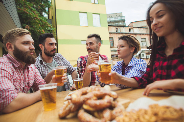 O grupo de amigos desfrutando de bebida no bar ao ar livre
 - Foto, Imagem