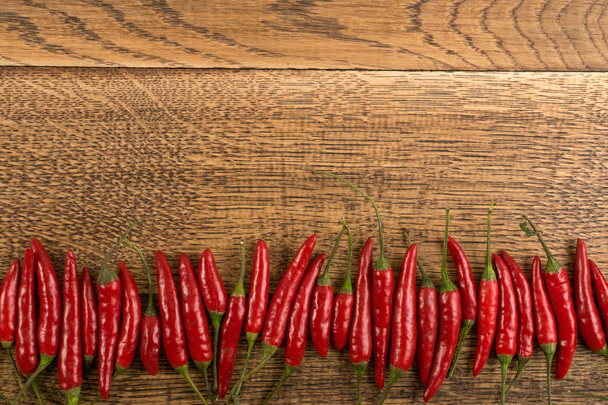 Very Hot Chili Peppers on Rustic Wooden Background Top View. Red Spicy Chilli Peppers Pattern or Backdrop for the Indian Menu for Oriental Food Design - Foto, Imagem