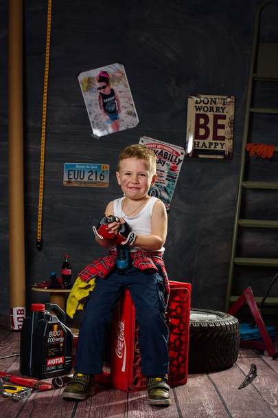 Маленький хлопчик у вигляді на авто механік в гаражі - Фото, зображення