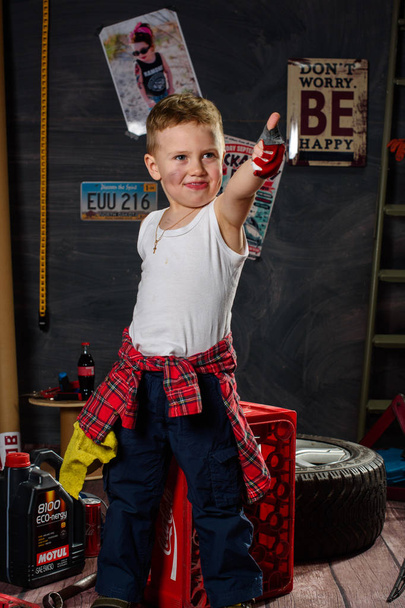 Ein kleiner Junge in Form eines Automechanikers in der Garage - Foto, Bild