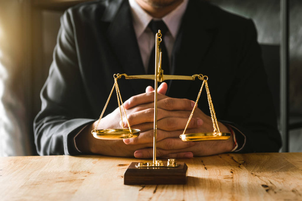 Justitie en wetgeving concept. Mannelijke advocaat in het Bureau met koperen schaal op houten tafel in ochtend licht - Foto, afbeelding
