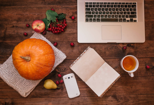 Felülnézet, egy tök, alma és egy könyv, telefon, laptop, a fából készült asztal. - Fotó, kép