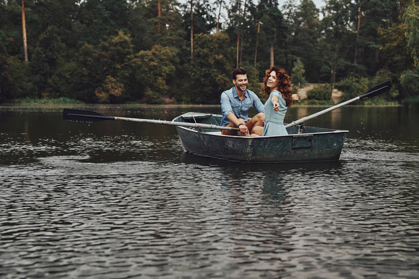 beautiful young couple enjoying romantic date and smiling while rowing a boat - Foto, Imagen