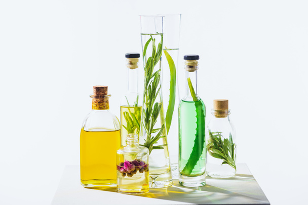 бутылки натуральных травяных эфирных зеленых и желтых масел на белой поверхности
 - Фото, изображение