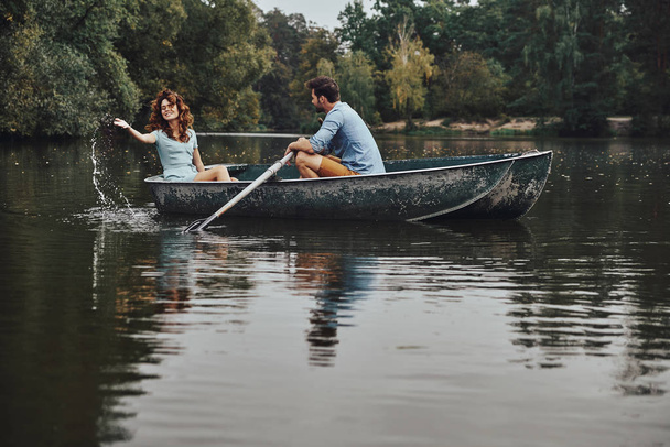 beautiful young couple enjoying romantic date while rowing a boat - Фото, изображение