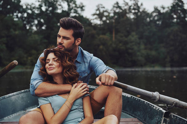 beautiful young couple embracing in boat on river  - Фото, изображение