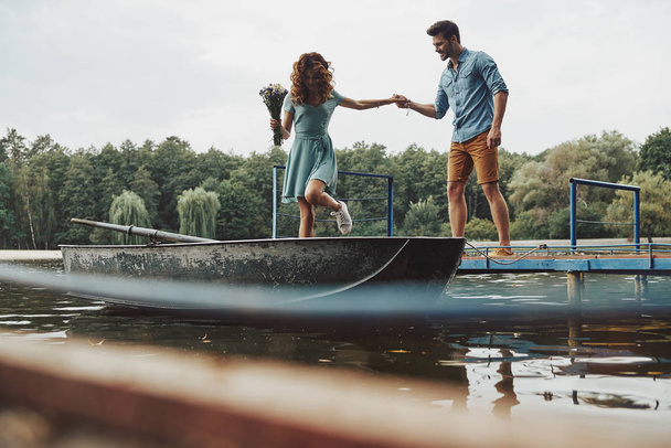 happy loving couple getting ready to row boat while enjoying date outdoors in lake in forest  - Foto, afbeelding