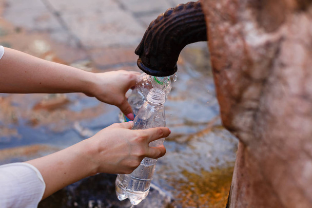 Наполнение бутылки питьевой водой в общественном фонтане, Рим, Италия
 - Фото, изображение