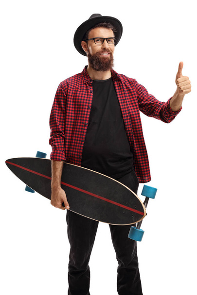 Hipster holding a longboard making a thumb up sign isolated on white background - Photo, image