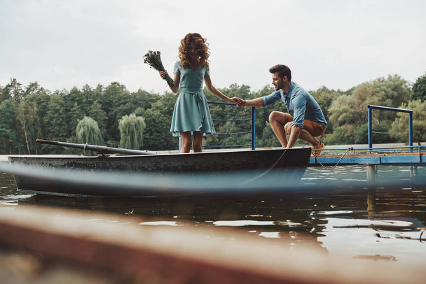 happy loving couple getting ready to row boat while enjoying date outdoors in lake in forest  - Foto, Bild