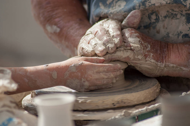 closeup of hands of old man with child making clay pottery in outdoor  - Foto, Bild