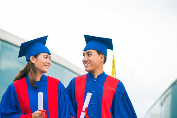 Estudiantes con sombreros de graduación mirándose
 - Foto, imagen