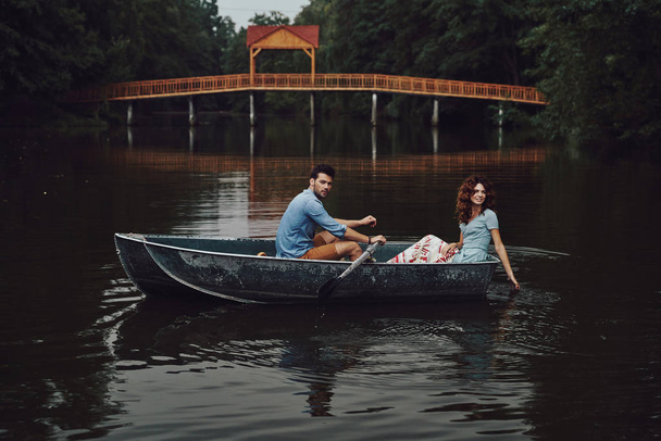 caucasian couple enjoying romantic date on lake in forest with trees and bridge  - Fotoğraf, Görsel