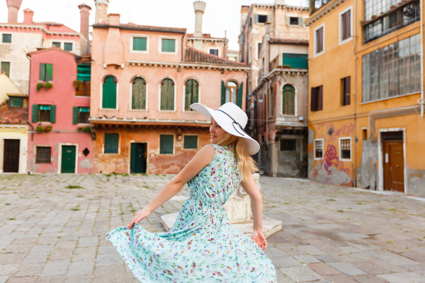 Woman wearing blue dress and white hat walking in street in Venice, Italy - Photo, Image
