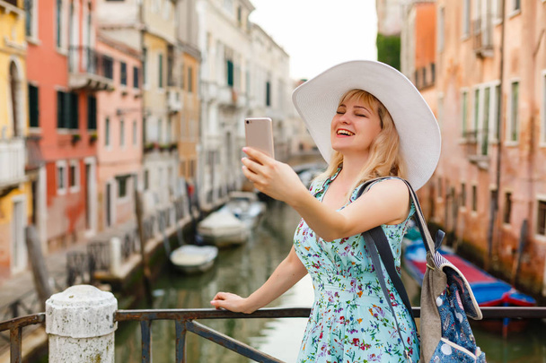Young female traveler making selfie photo using her smartphone standing near San Marco square with gondolas on the background in Venice, Italy - Fotoğraf, Görsel