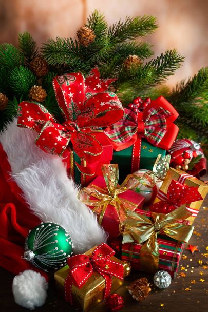 Composición navideña con sombrero rojo de Santa Claus, bolas de Navidad y cajas de regalo sobre fondo de madera
 - Foto, imagen