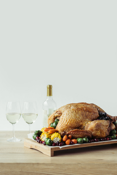 close up view of festive thanksgiving dinner table set with glasses of wine, roasted turkey and vegetables on wooden tabletop on grey backdrop - Foto, Imagem