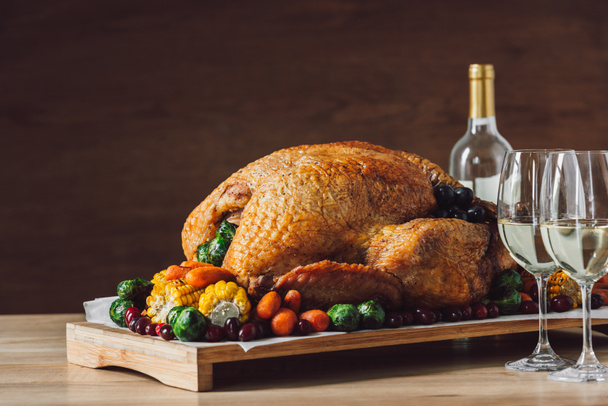 close up view of traditional roasted turkey, vegetables and glasses of wine for thanksgiving dinner - Photo, image