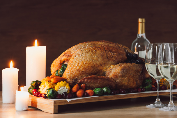 木製卓上の感謝祭の夕食のキャンドル、伝統的な七面鳥のロースト、野菜やワインのグラスのビューを閉じる - 写真・画像
