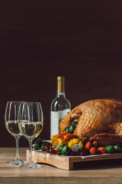 close up view of traditional roasted turkey, vegetables and glasses of wine for thanksgiving dinner - Фото, изображение