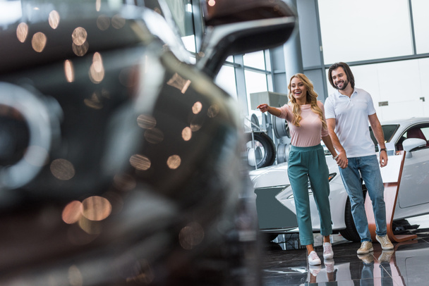 young couple choosing automobile at dealership salon - Foto, afbeelding