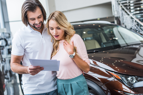 portrait of couple with catalog choosing car at dealership salon - Photo, Image
