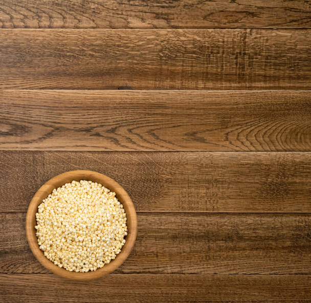 Διογκωμένο κεχρί σνακ σε ξύλινο Στρογγυλό μπολ με Copyspace. Υγιεινά δημητριακά χορτοφάγος ή Vegan φαγητό στο τραπέζι από ξύλο το Top View για διαφήμιση προϊόντος - Φωτογραφία, εικόνα