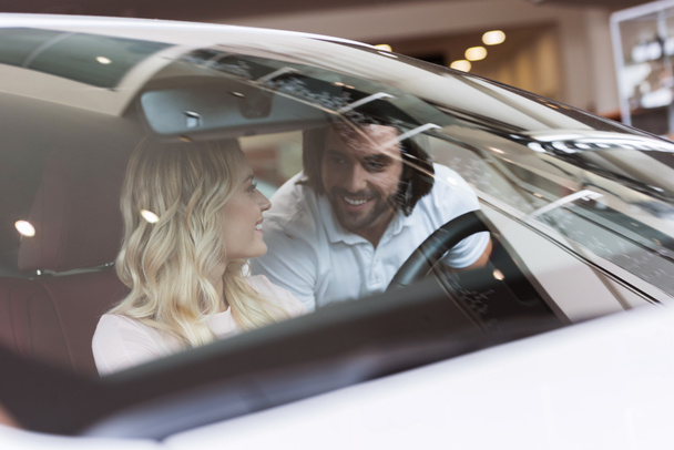 sorridente giovane coppia con auto nuova in salone di auto
 - Foto, immagini