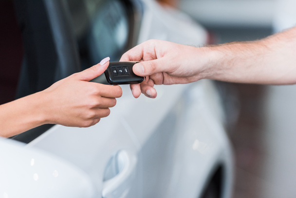 cropped shot of man giving car key to woman at dealership salon - Photo, Image