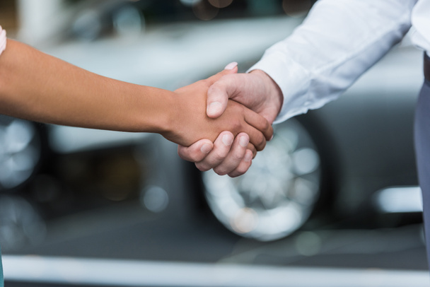 cropped shot of dealership salon shop assistant and female customer shaking hands in auto salon - Fotoğraf, Görsel