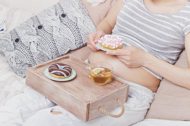 Schwangere mit verschiedenen Donuts auf dem Teller, weicher Fokus Hintergrund - Foto, Bild
