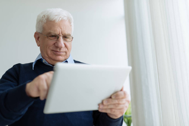 Старший чоловік в окулярах вчиться використовувати планшетний комп'ютер
 - Фото, зображення
