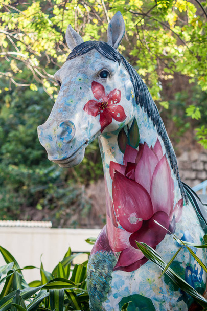 Kunstobjekt auf der Straße, bemaltes Pferd in Nahaufnahme, mit Blumen und Lotos - Foto, Bild